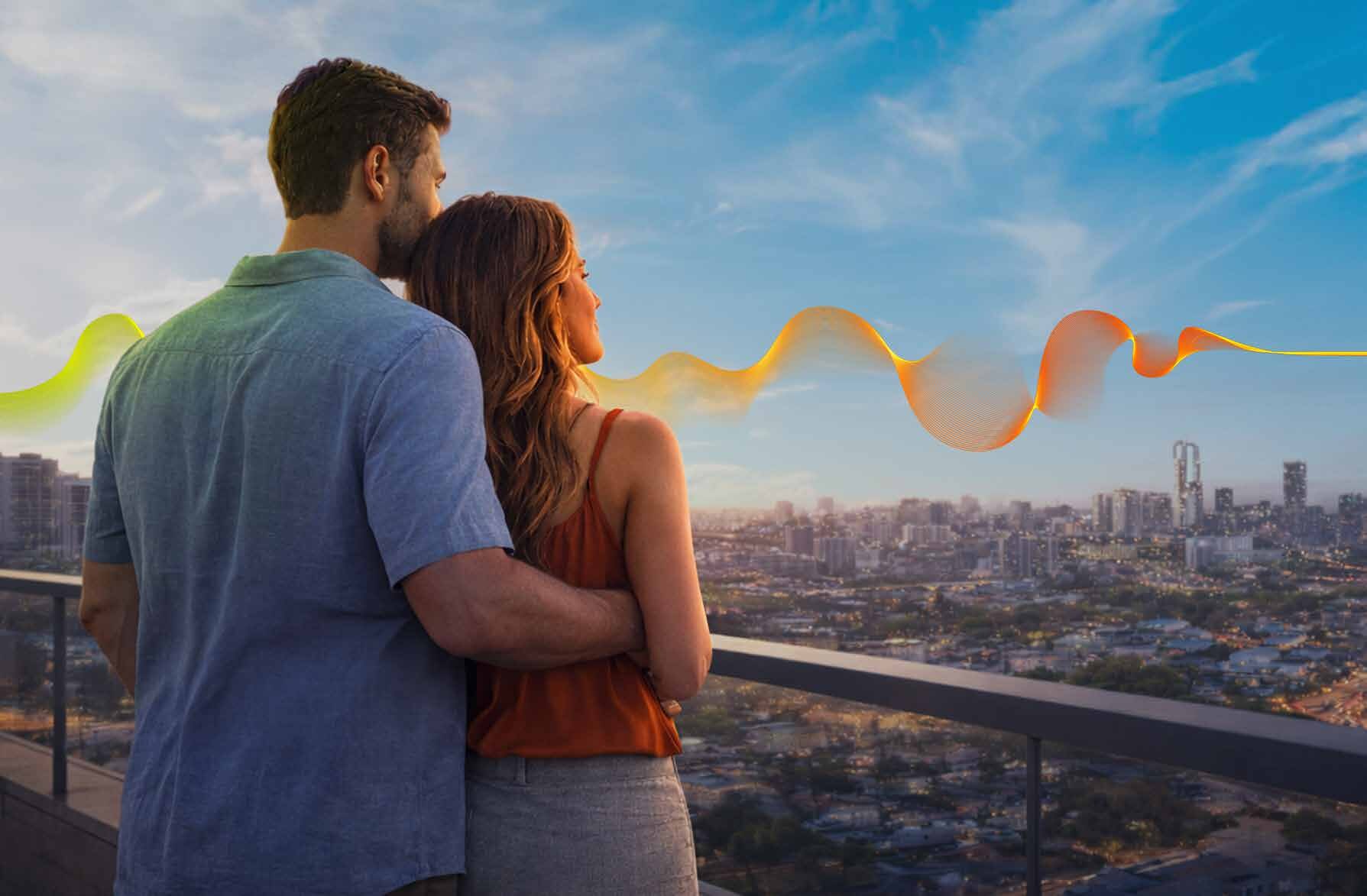 Casal na varanda de um apartamento do Conexão Anhembi olhando o skyline de São Paulo ao entardecer